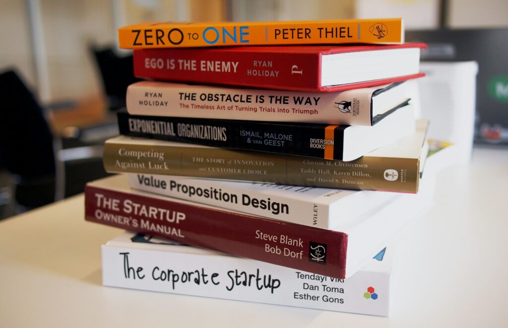 Tumpukan buku bisnis dan pengembangan startup di atas meja. cara mudah membaca buku